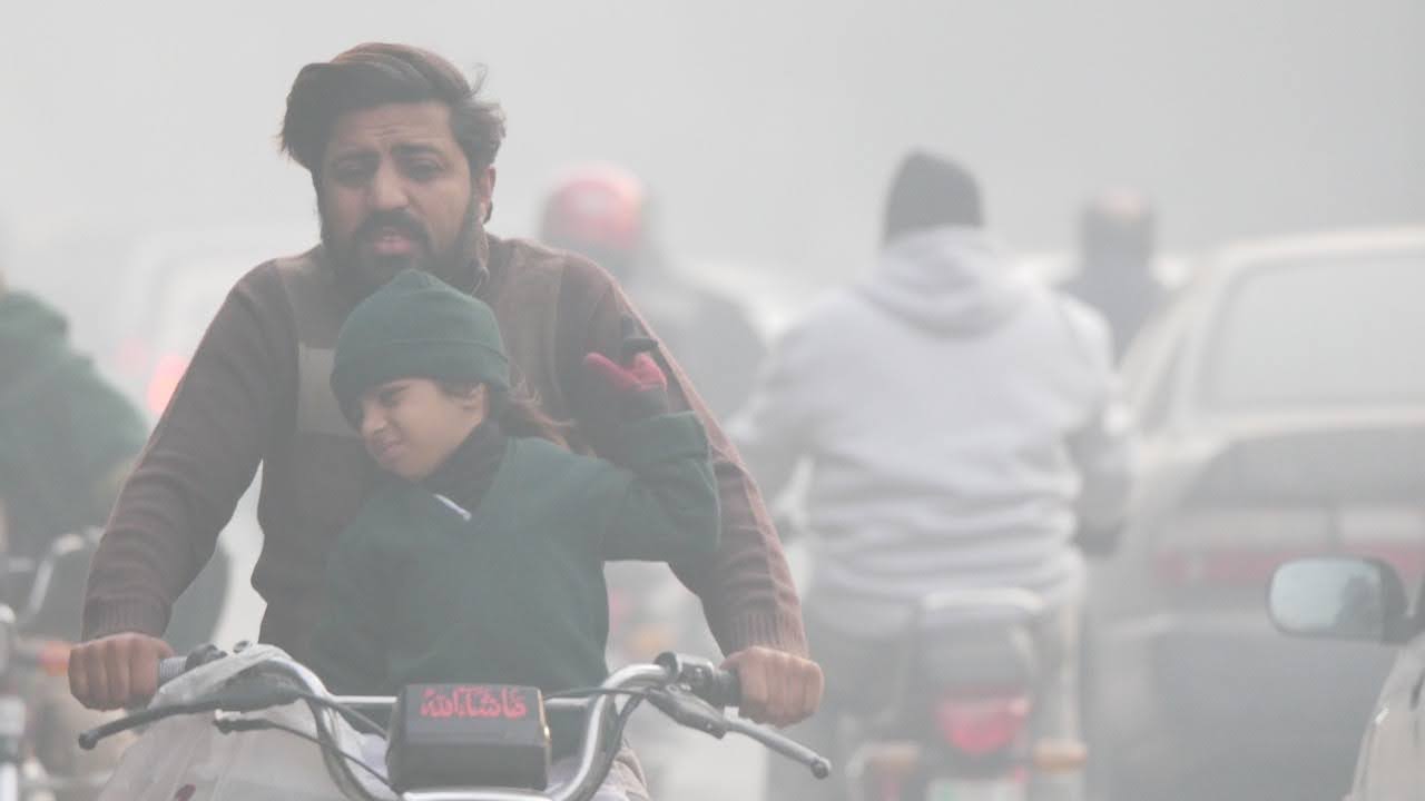 A father going to drop off his son at school during a Lahore winter morning